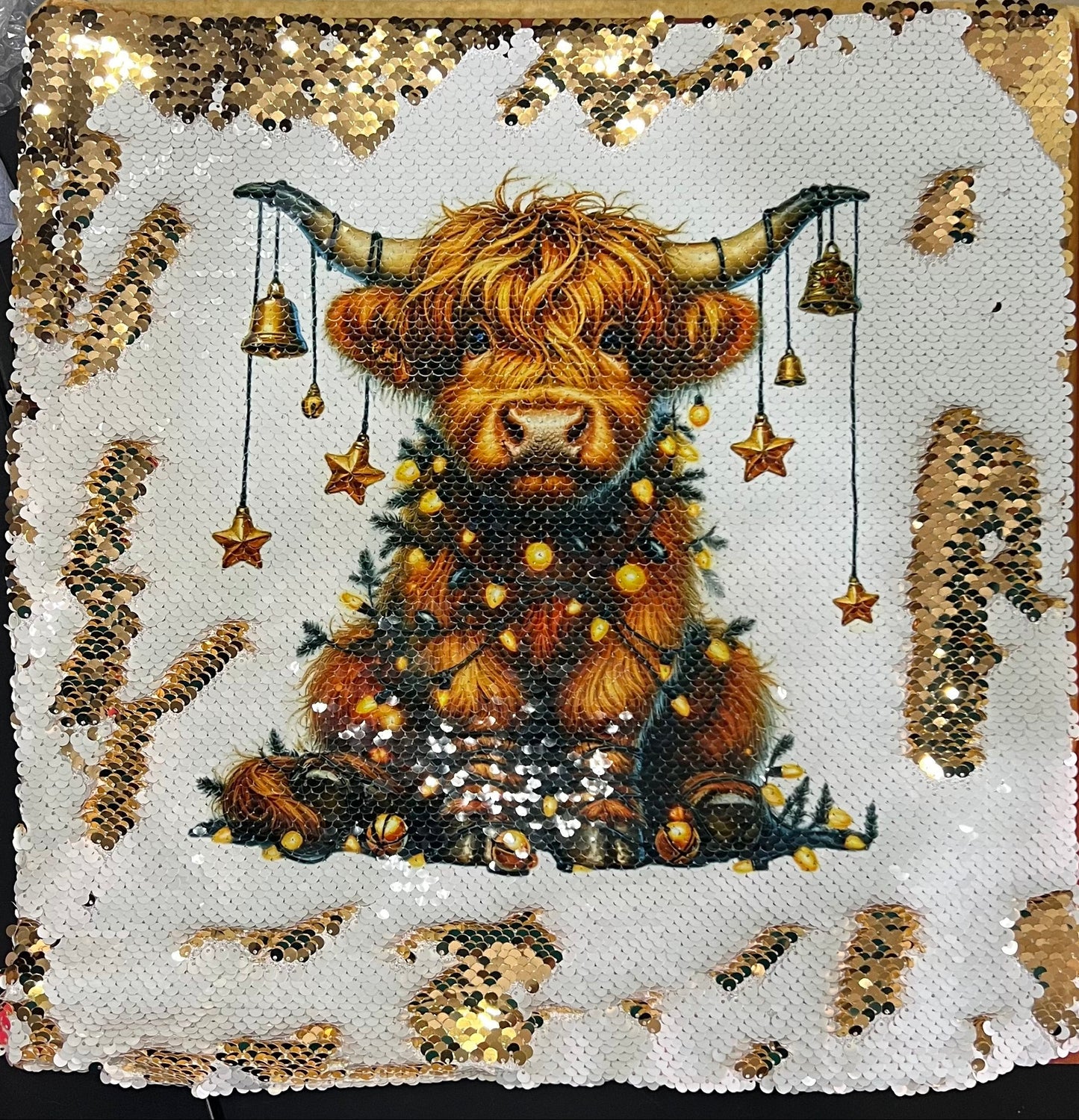 Decorative pillow with a Highland cow design on a sequined background