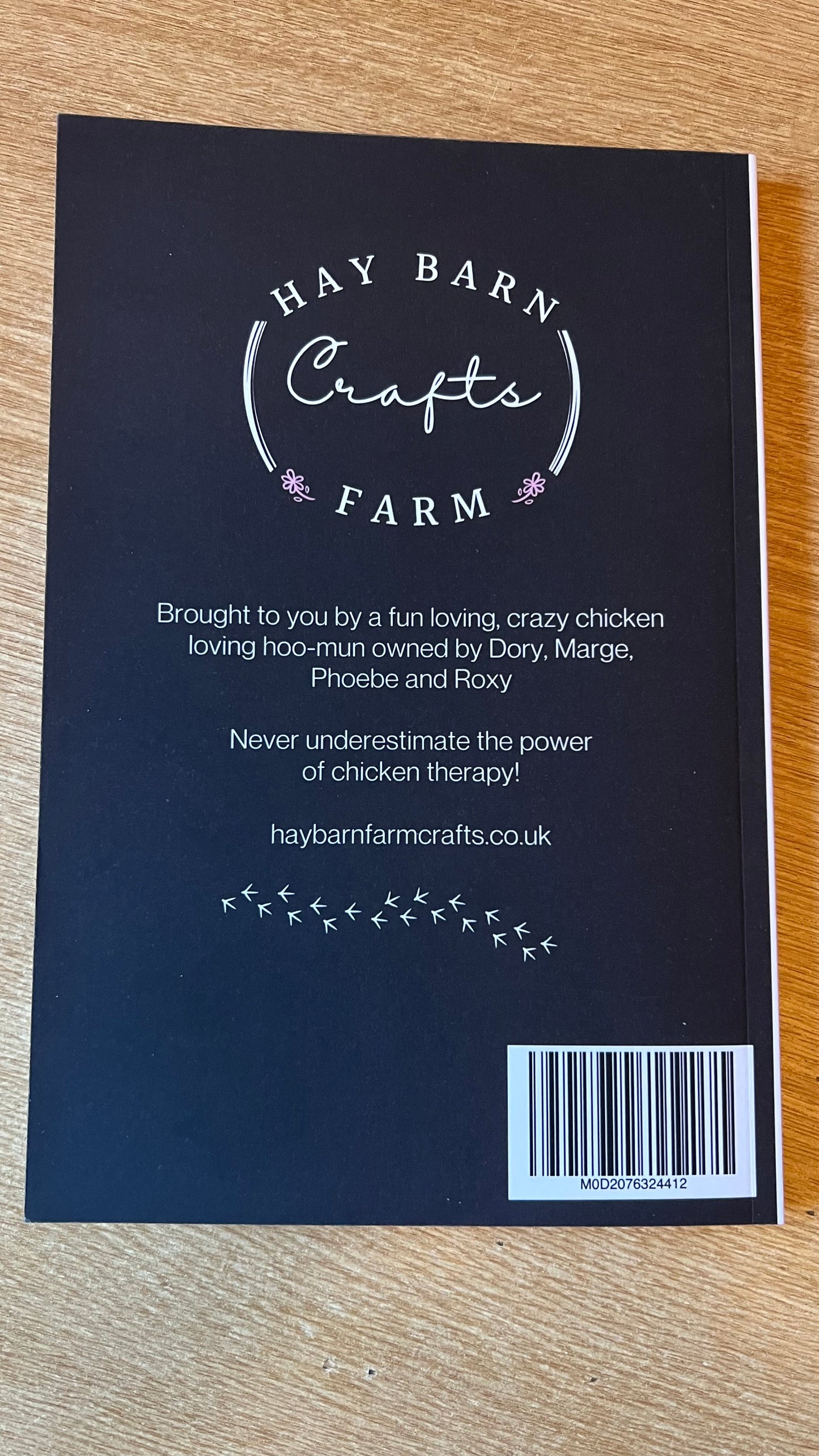 The rear of a notebook which has Hay Barn Farm Crafts logo and a a brief description as to the inspiration on the notebook which was brought to you by a fun loving hoo-mun owned by Dory, Marge, Phoebe and Roxy with the words Never underestimate the power of chicken therapy.