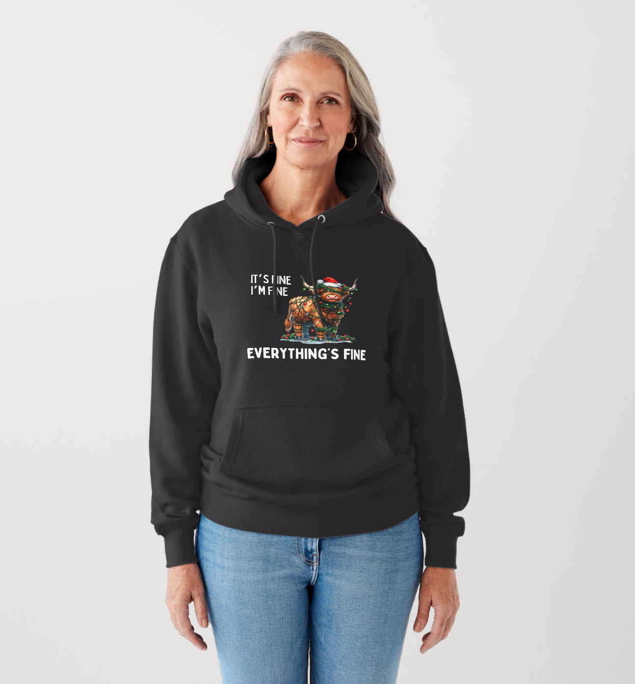 Person wearing a black hoodie with a Festive design being a Highland Cow tangled in fairy lights and the text around it reads 'It's Fine, I'm Fine, Everything's Fine'