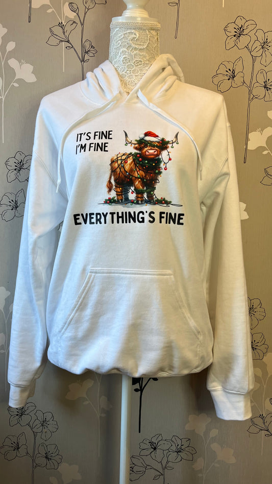 White hoodie with graphic design on a mannequin against a floral-patterned wall.