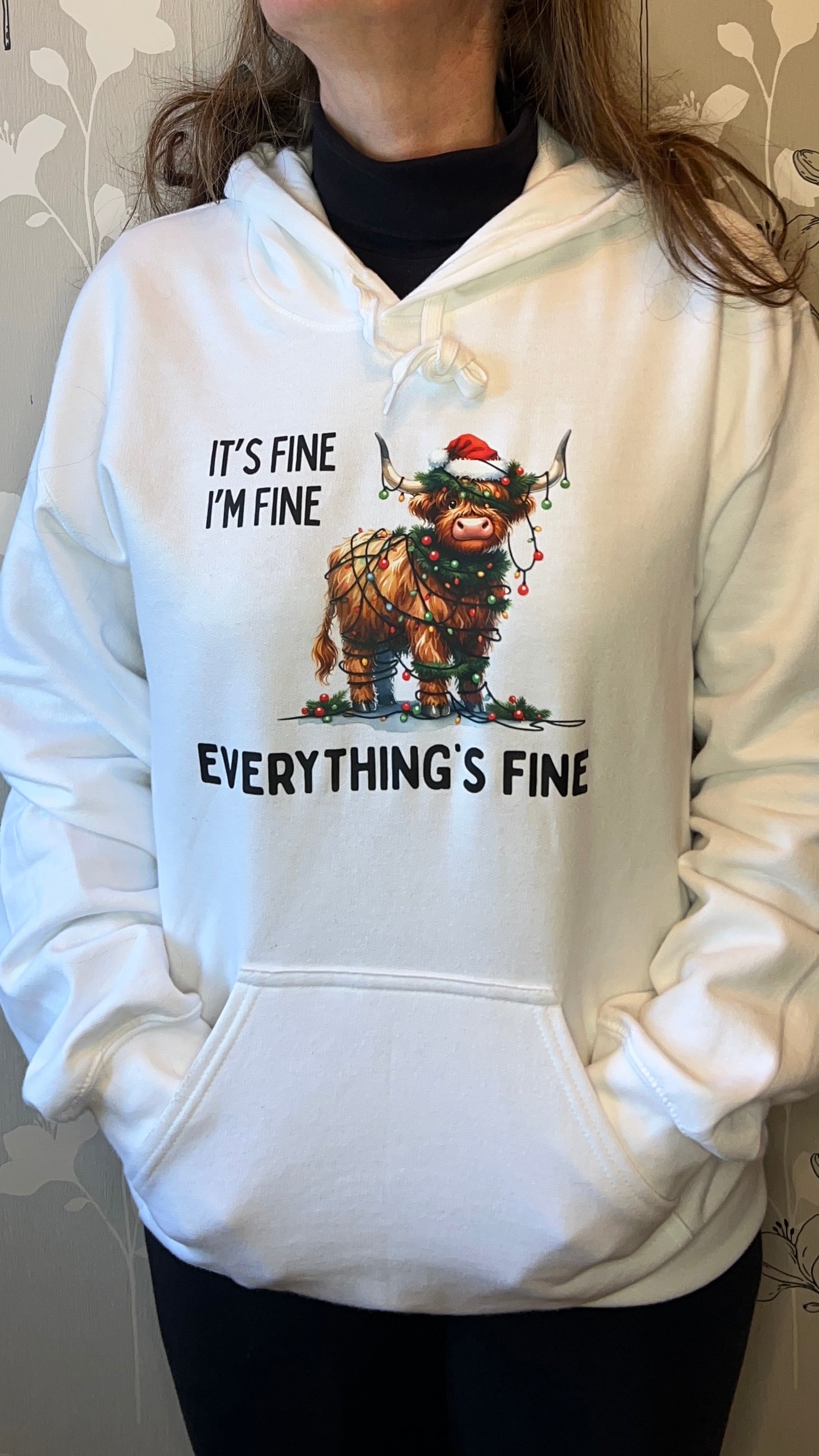 White hoodie with a graphic of a creature and text 'It's fine, I'm fine, everything's fine' worn by a person.