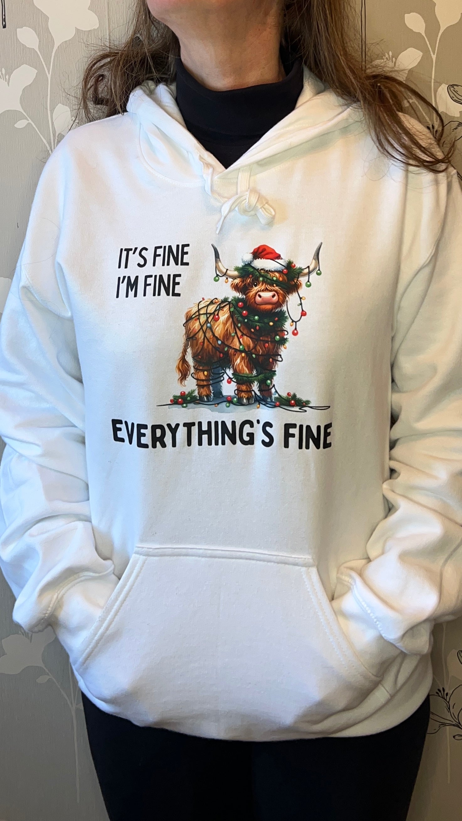 White hoodie with a graphic of a creature and text 'It's fine, I'm fine, everything's fine' worn by a person.