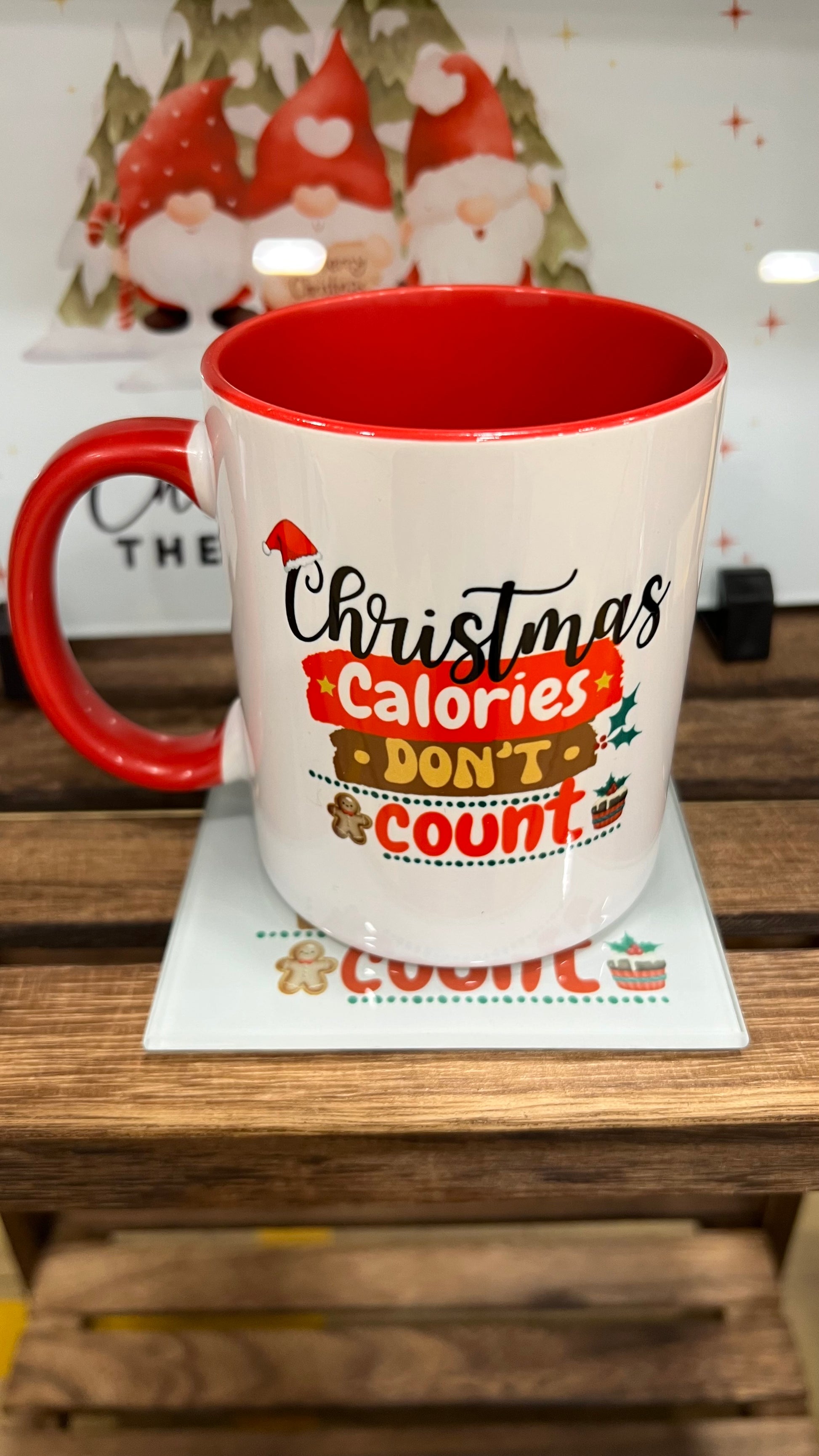 White mug with red interior and handle, featuring Christmas Calories Don't Count text on a wooden surface.
