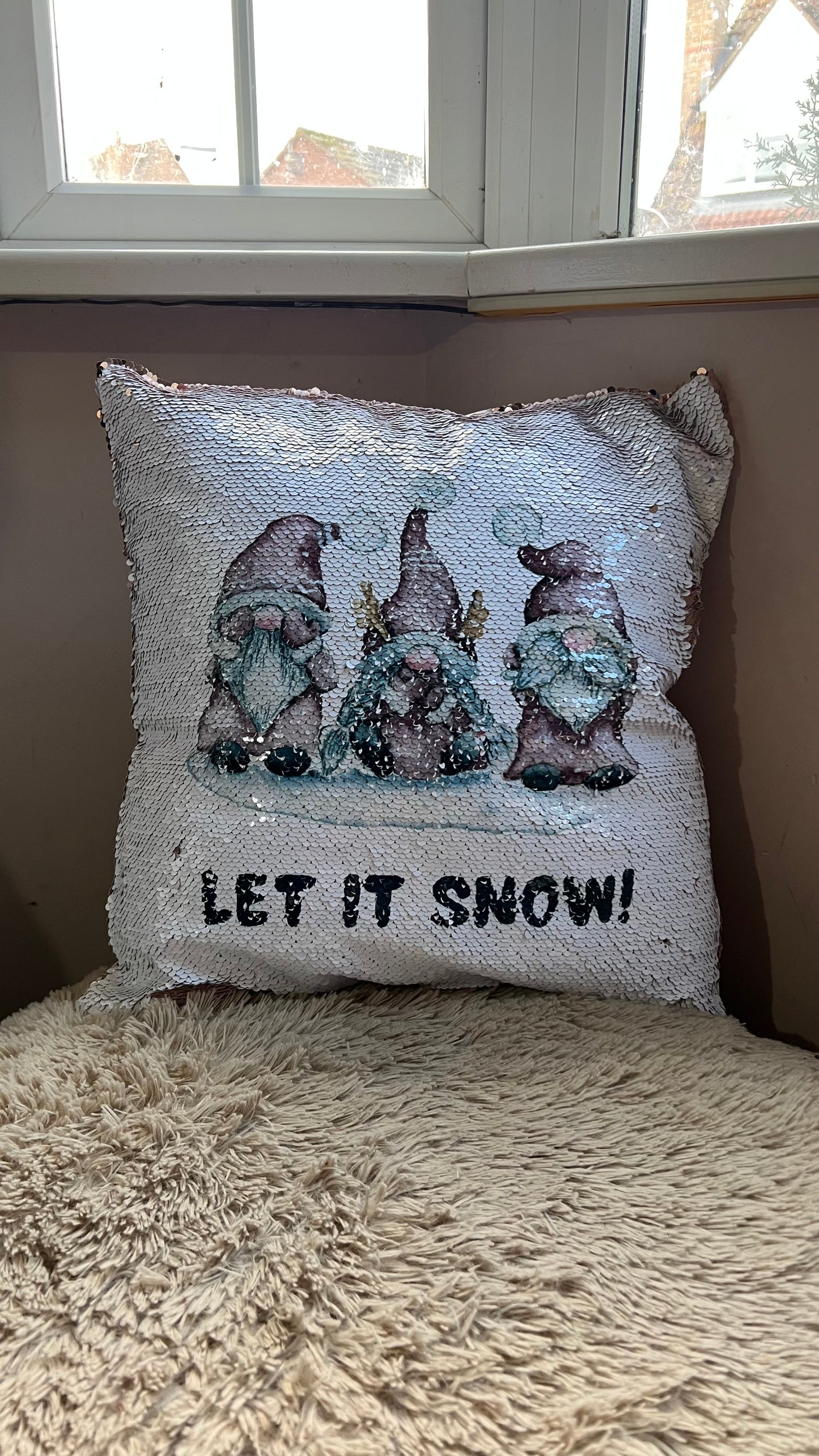 Decorative pillow with Christmas themed Gnome design and 'LET IT SNOW!' text, placed on a surface.