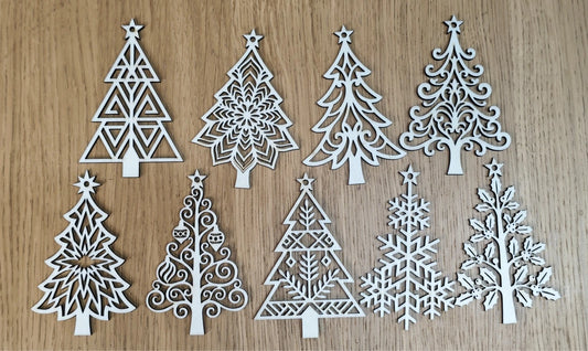 Nine white laser-cut wooden Christmas tree ornaments in various intricate patterns, arranged on a light brown wood grain background.