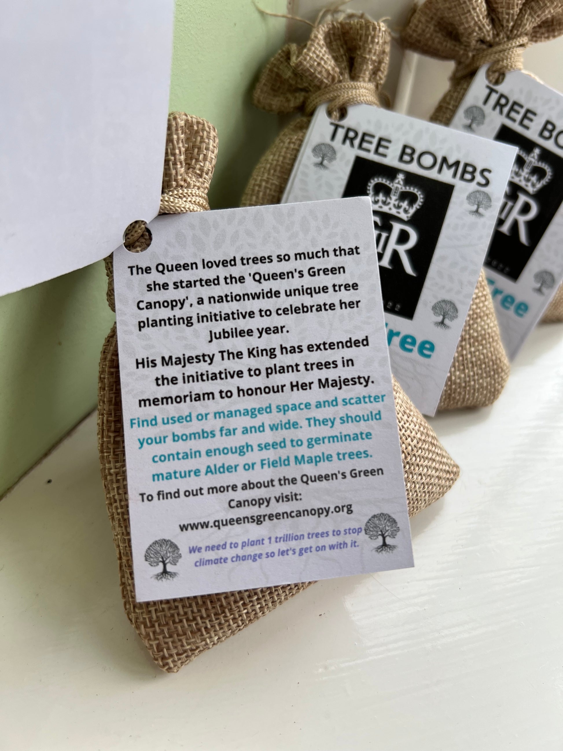 Image of a label attached to a small burlap gift bag. The label contains instructions on how to use seed bombs and also a website to find out more about the Queens Green Canopy